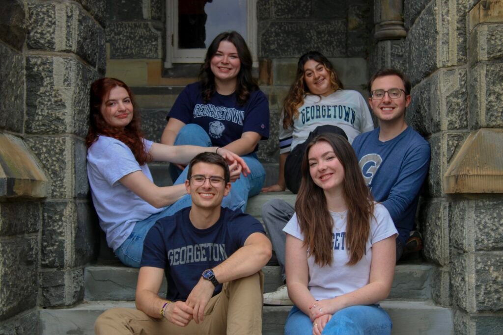 Keith Richards and five friends sit on the steps of Healy Hall wearing Georgetown shirts.