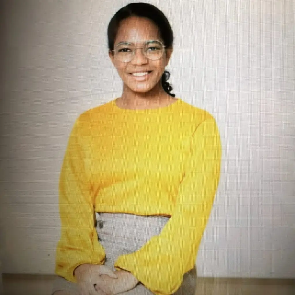 Kennedy Copeland wearing a plaid skirt and yellow blouse with glasses.