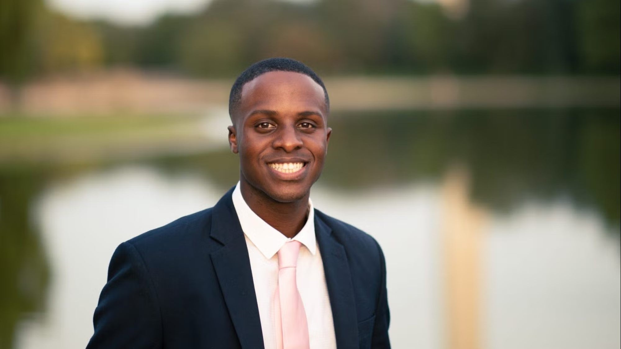 Kevin Russell Headshot, wearing navy blue blazer, white shirt, and light pink tie.