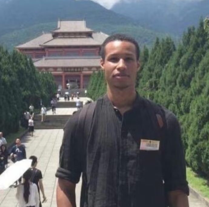 Khyle Eastin in front of a building with trees in the background.