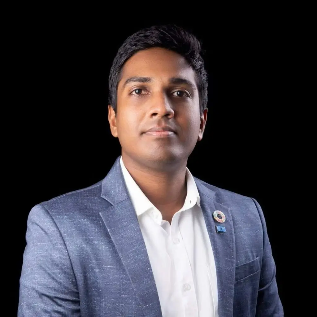Kulunu Jayamanne wearing a blue blazer with pins and a white button down shirt.