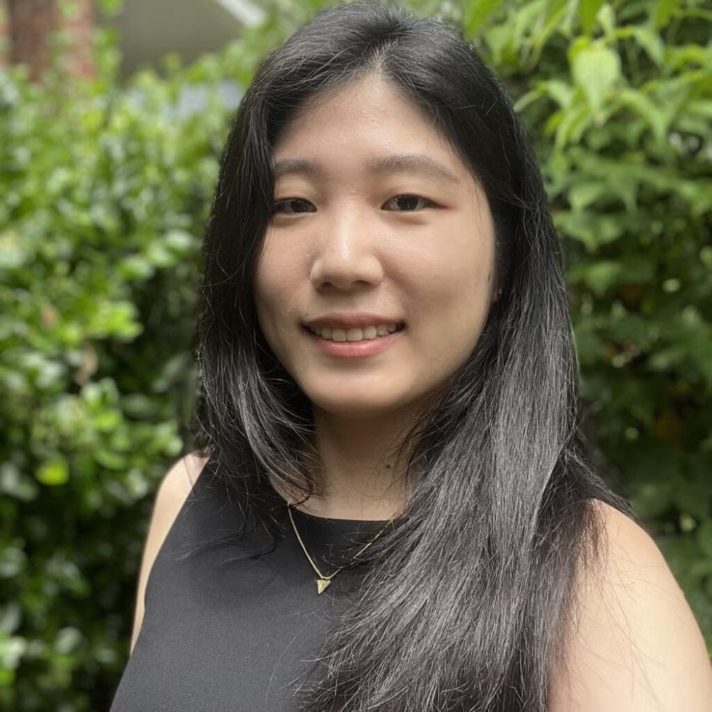 Laura Lee wearing a black blouse and a gold triangle necklace.