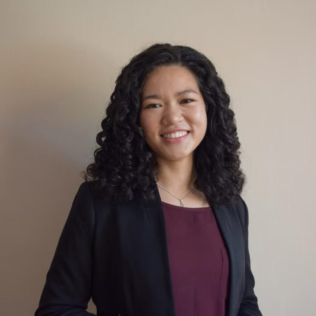 Linh Nguyen wearing a black blazer and burgundy shirt.
