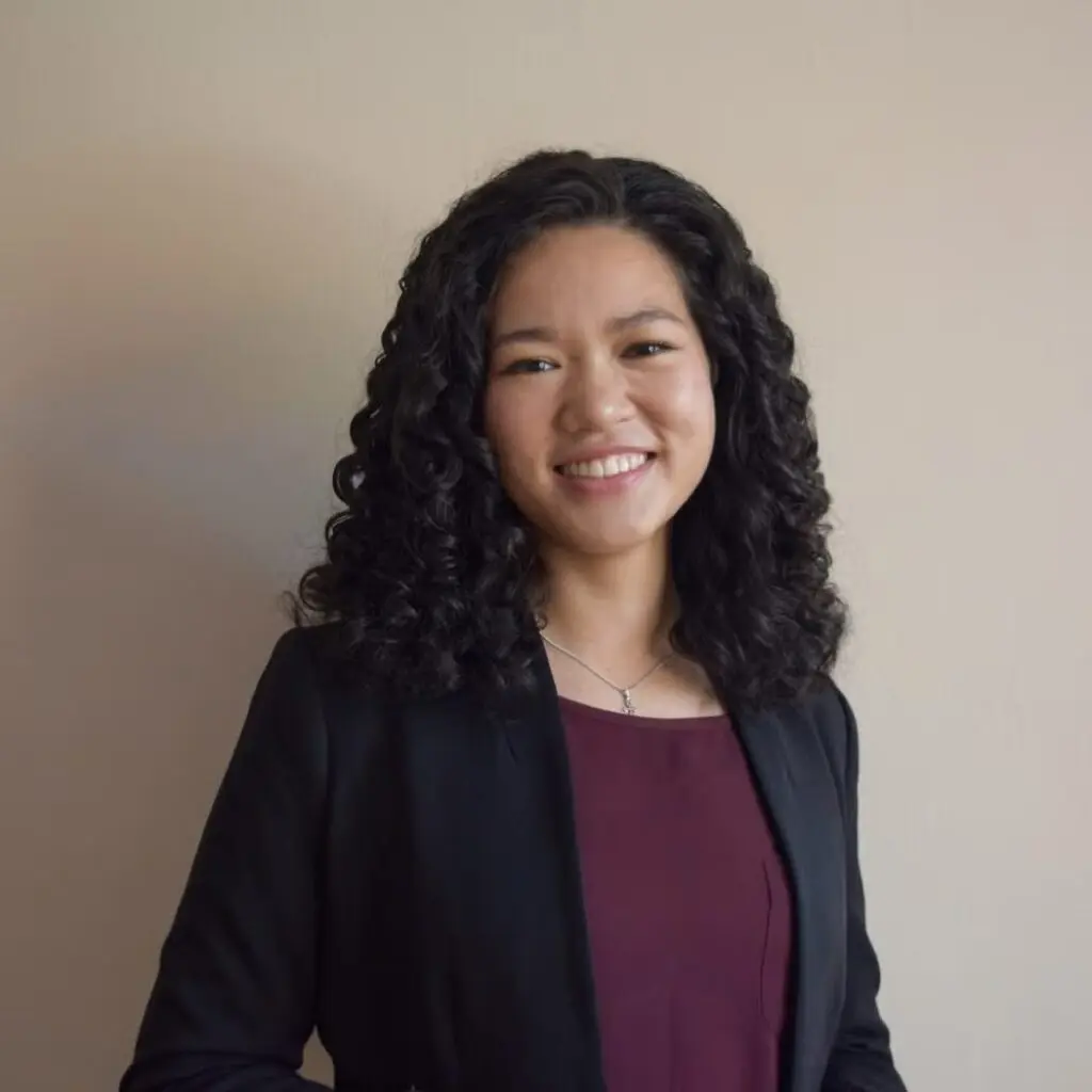 Linh Nguyen wearing a black blazer and burgundy shirt.