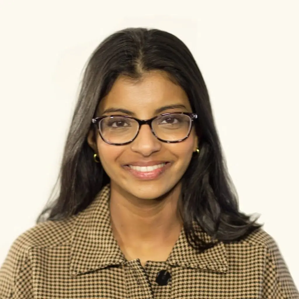Mariam Malik wearing a tan and black checkered, blazer and glasses.