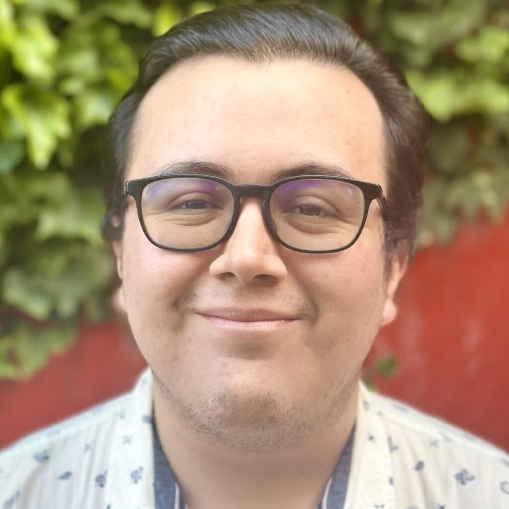 Miguel Navarro wearing a white shirt with a blue pattern and glasses.