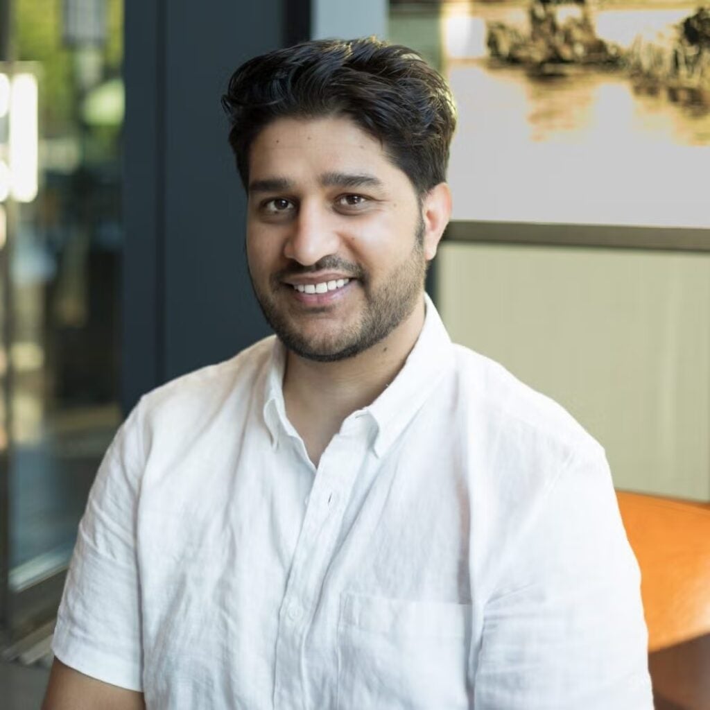 Nabin Dhimal wearing a white button down shirt and smiling