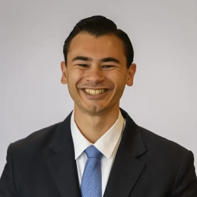 Nathan Kumar wearing a black suit and light blue tie.