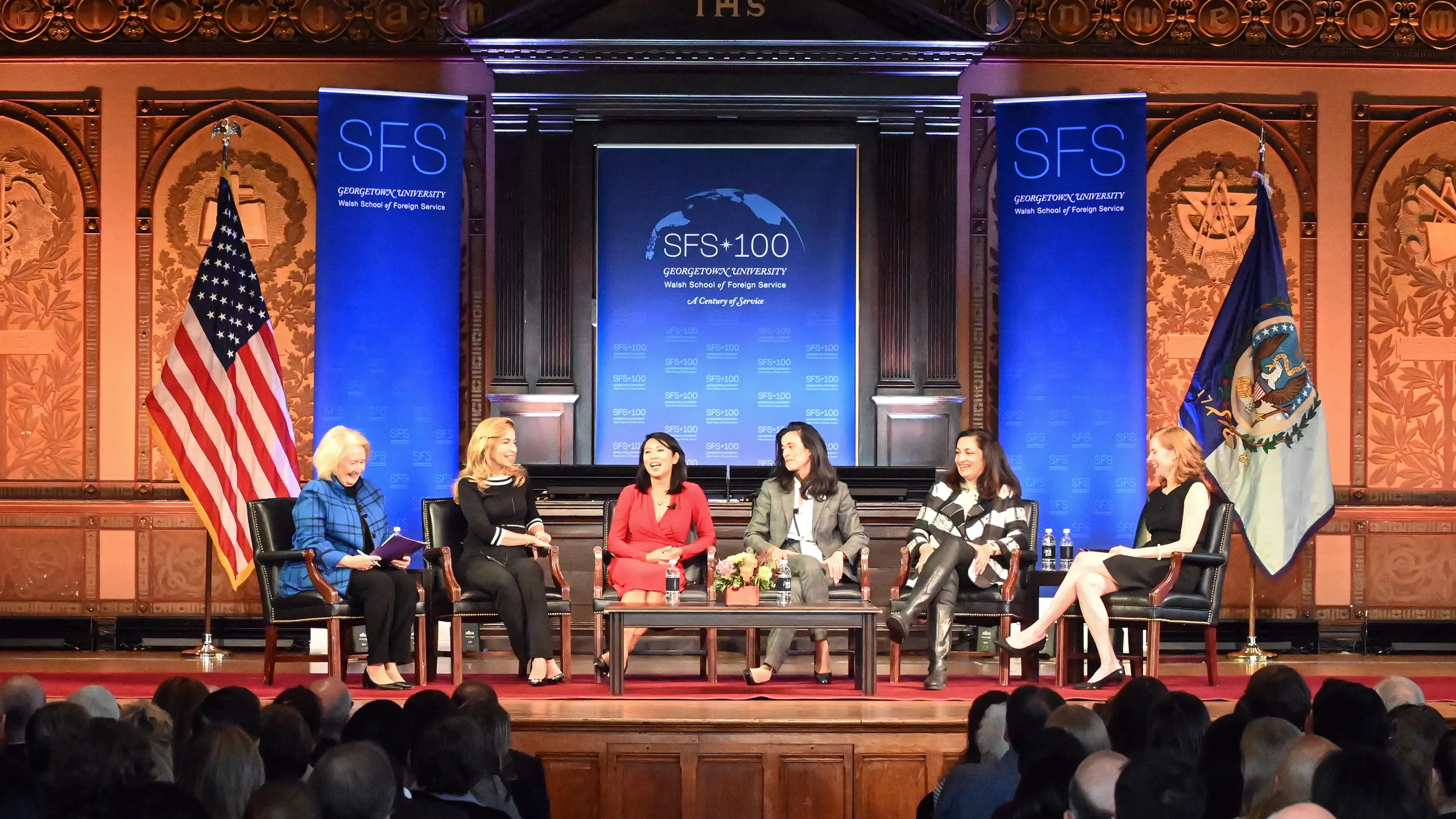 Six women speaking in a panel on stage. Behind them, banners for the SFS 100. In front of them an audience.