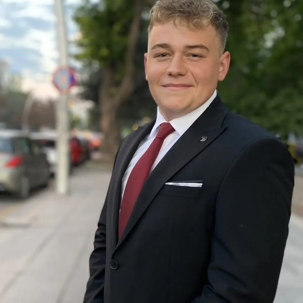 Sam Frykholm wearing a black blazer and a burgundy tie