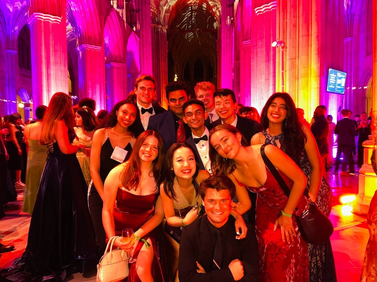 Sam Li poses with a group of friends in evening attire at a fancy venue.