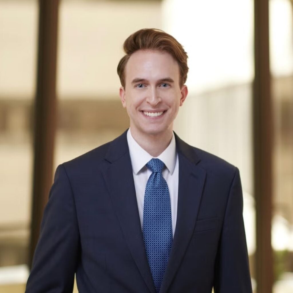 Solomon Bennett wearing a navy blue suit and a blue tie with a white button-down shirt.