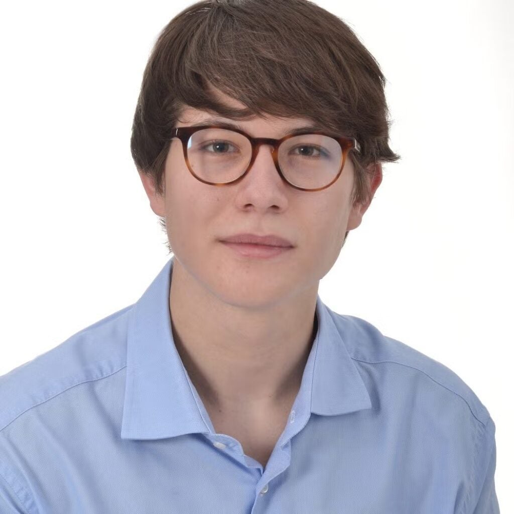 Sprydon Spiros Spyromilios wearing a blue button-down shirt and glasses.