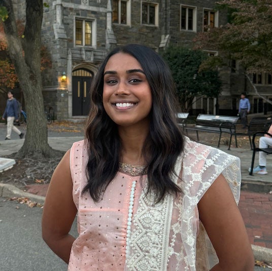 Headshot of Sreya Patri smiling at the Georgetown campus, wearing a pink embroidered dress.