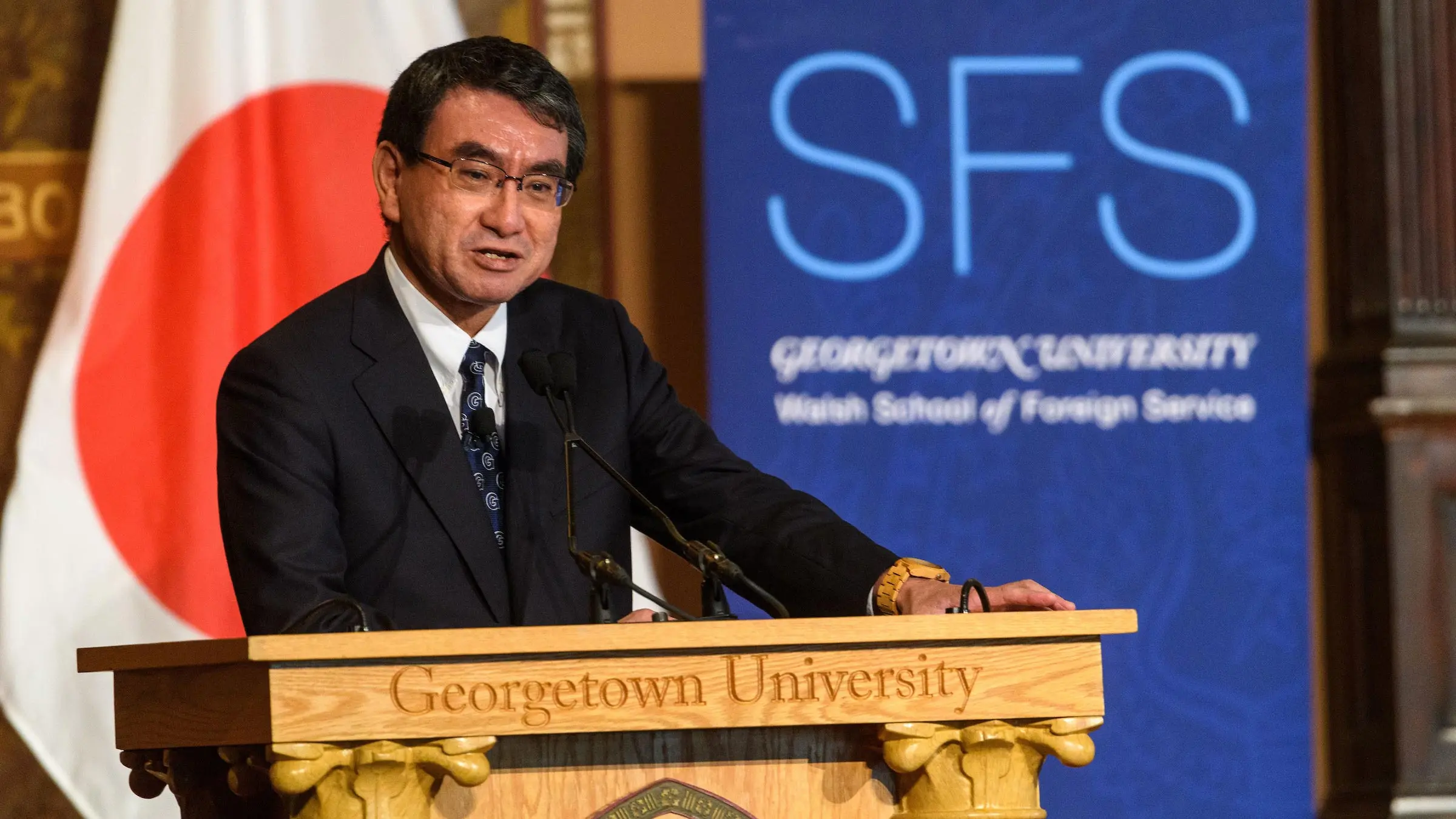 Japanese Foreign Minister Taro Kono in front of a podium. Behind him the flag of Japan.