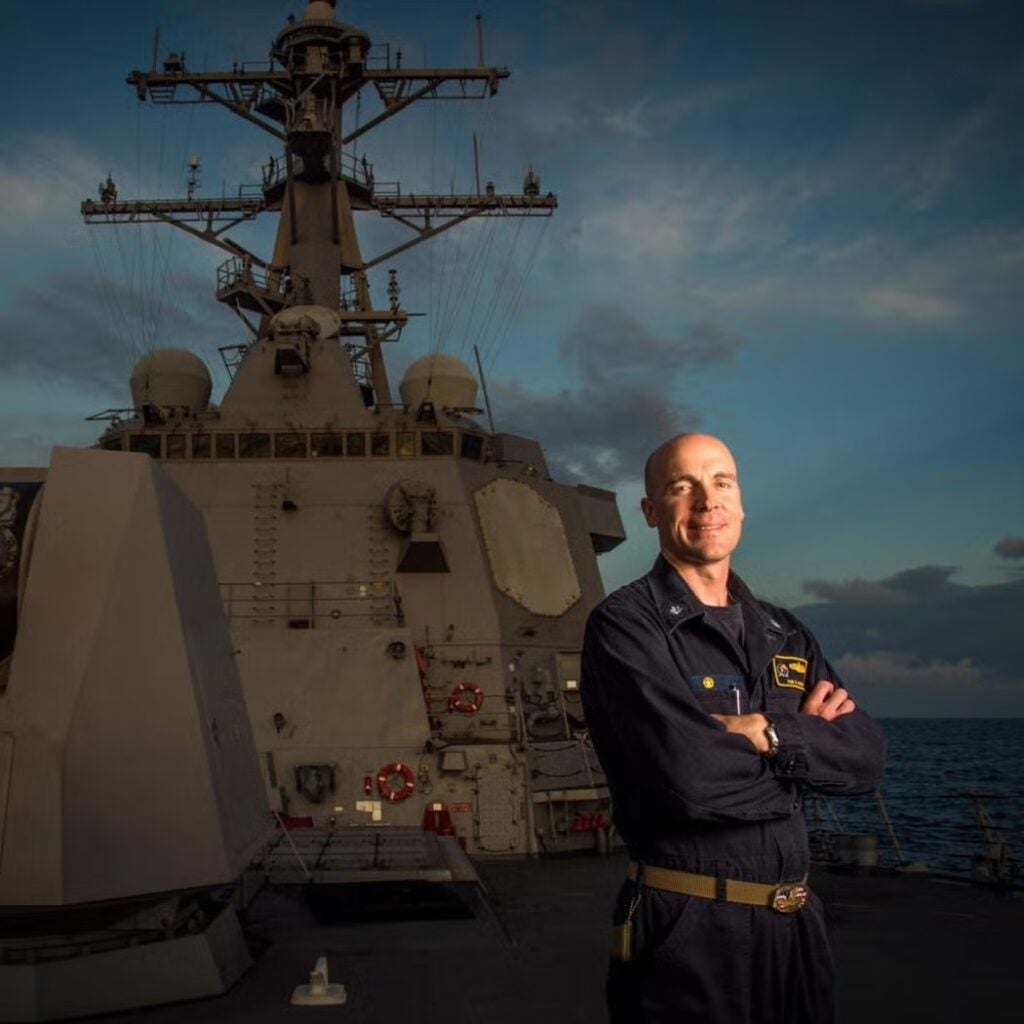 Tom Ogden wearing a uniform and standing on a ship.