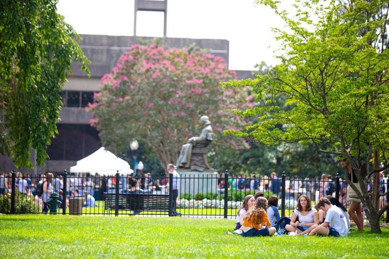 students having a picnic on campus. In the background John Carroll statue and more students walking around campus.