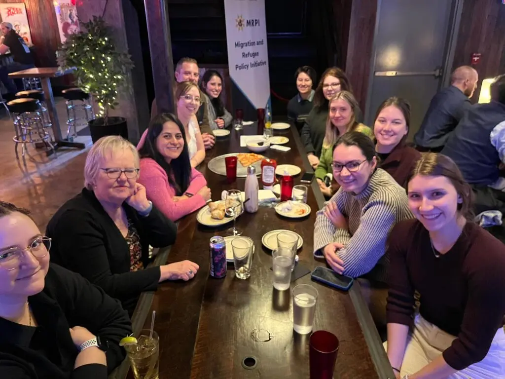 Angie Wright sits at a table eating a meal with Professor Elizabeth Ferris and fellow students.