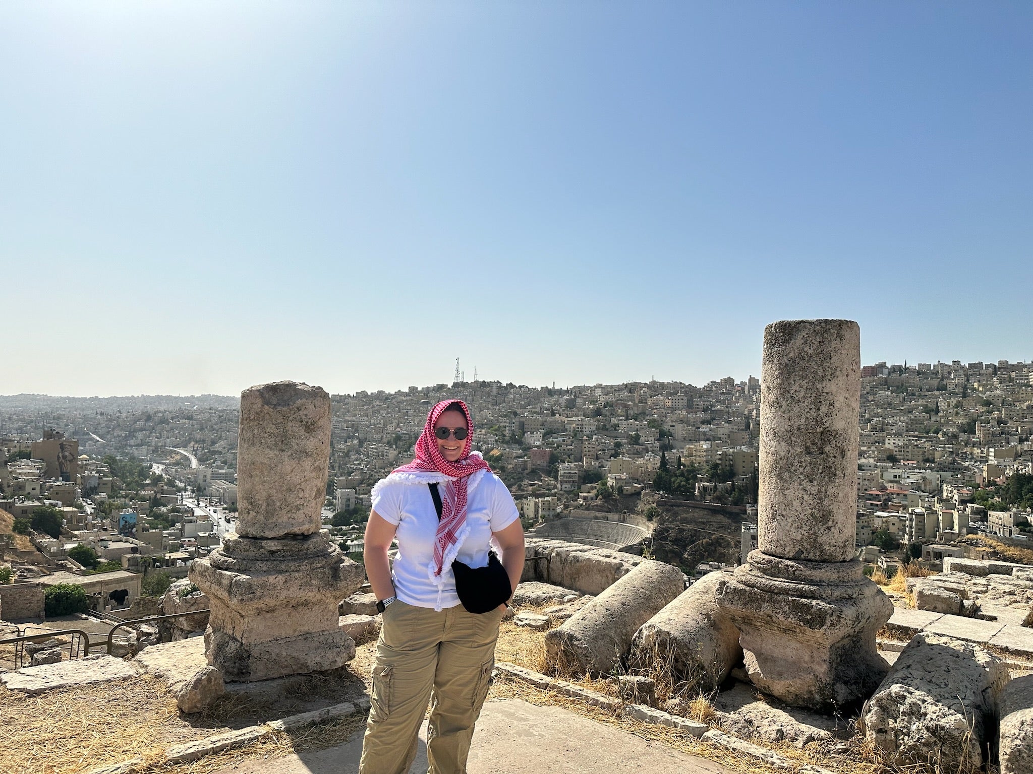Angie Wright stands on top of the Amman Citadel wearing a red and white kaffiyeh wrapped around her head.