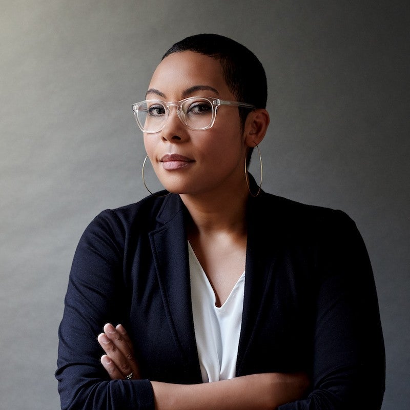 Headshot of Racquel Gates with her arms crossed in front of her, waring a navy blazer, half smiling at the camera.