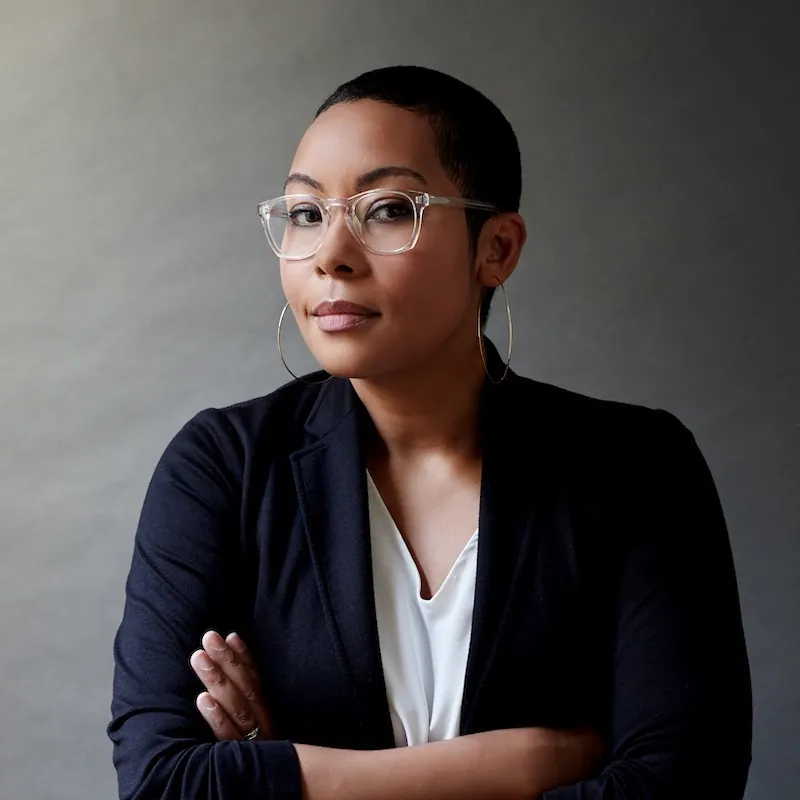 Headshot of Racquel Gates with her arms crossed in front of her, waring a navy blazer, half smiling at the camera.