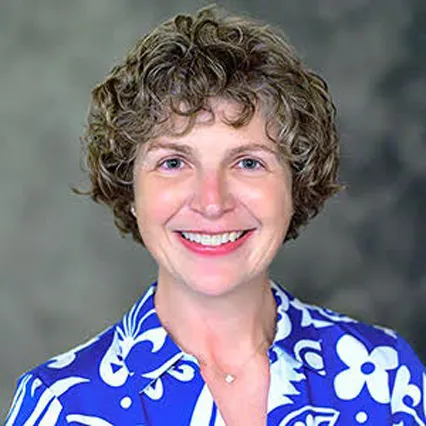Headshot of Kay Summers smiling, wearing a bright blue blouse with white flowers.