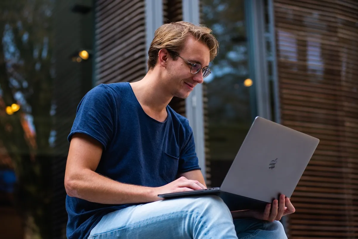 Student sitting, smiling looking at laptop
