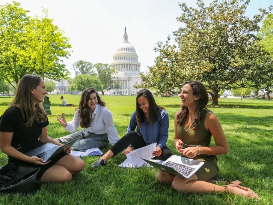 Four students sitting on the US Capitol lawn, talking and studying.
