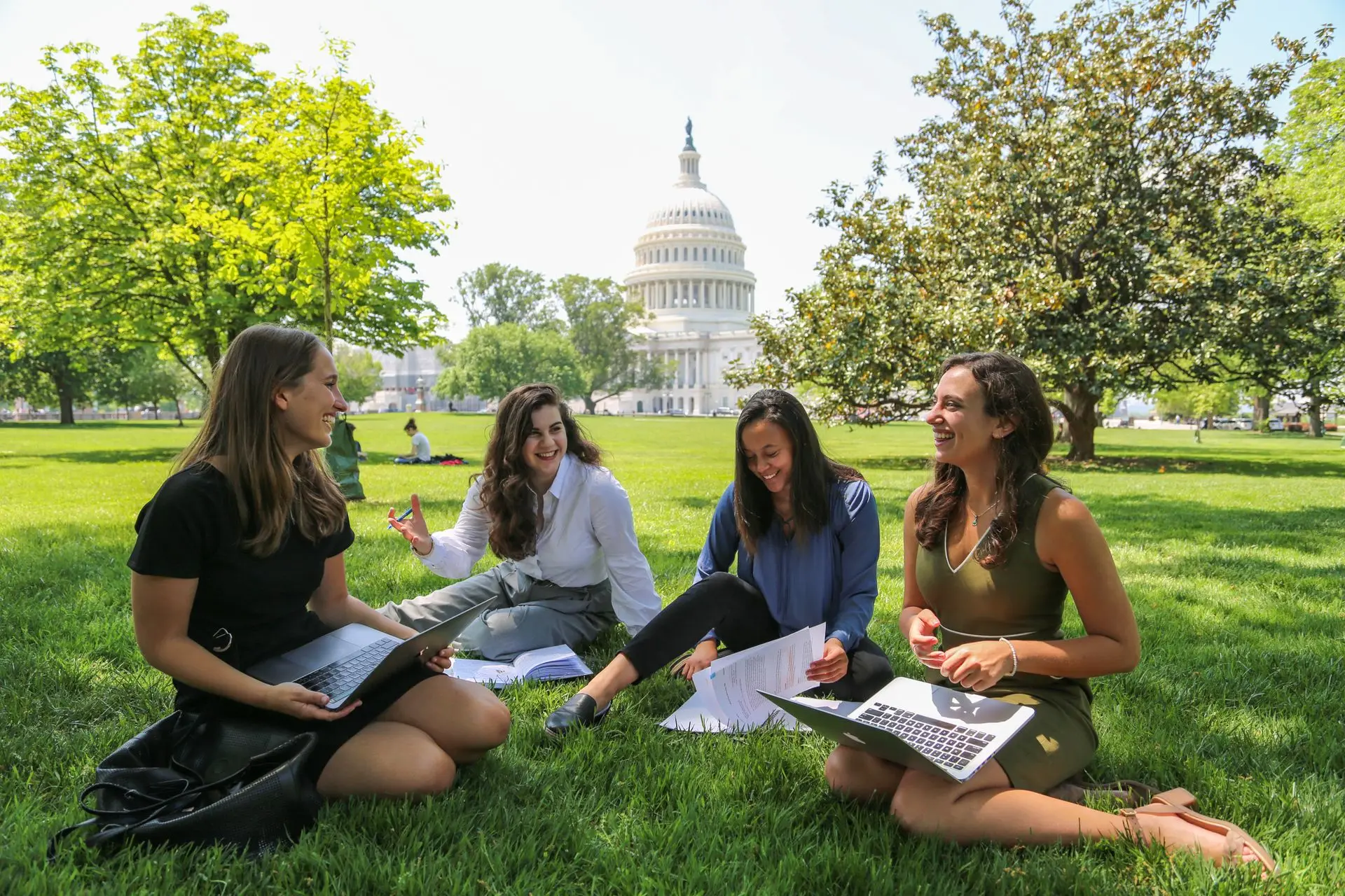 Four students sitting on the US Capitol lawn, talking and studying.