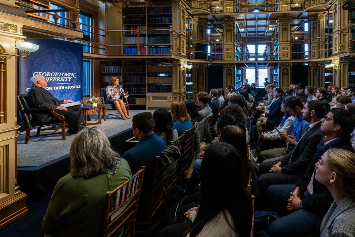Nancy Pelosi sitting on a stage being interviewed. There is an audience of students listening.