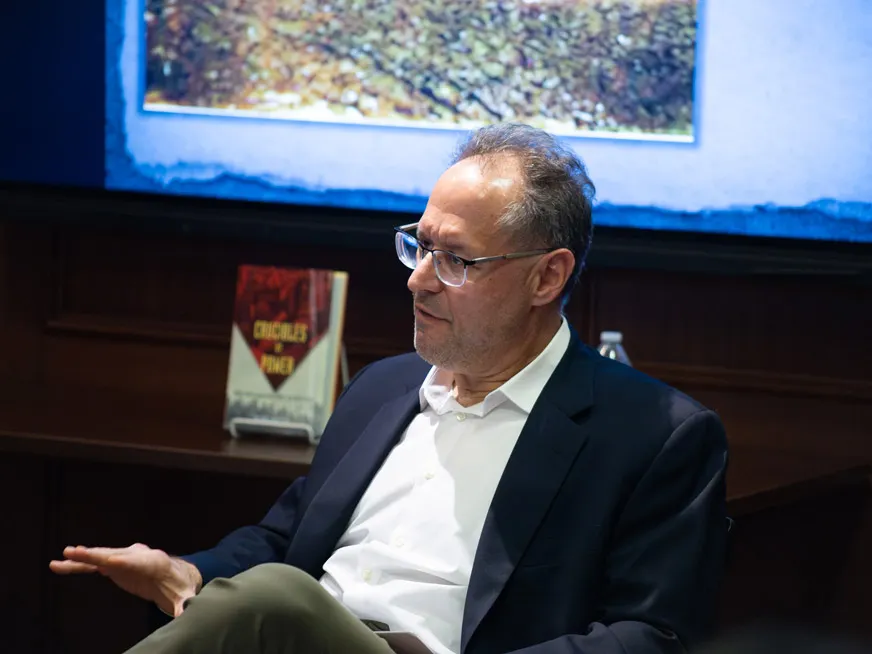 Michael David Fox sitting down, speaking. Behind him a book titled Crucibles of Power.
