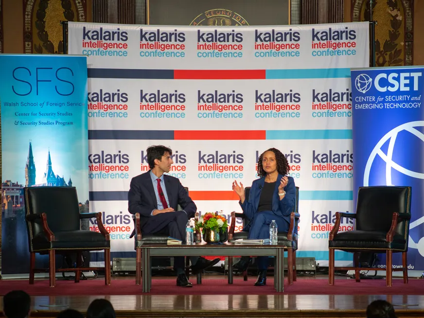 A man and a woman sitting on stage speaking at a panel. Behind them a sign with the words Kalaris intelligence conference. And two banners, one for the Center for Security Studies, and another for the Center for Security and Emerging Technology
