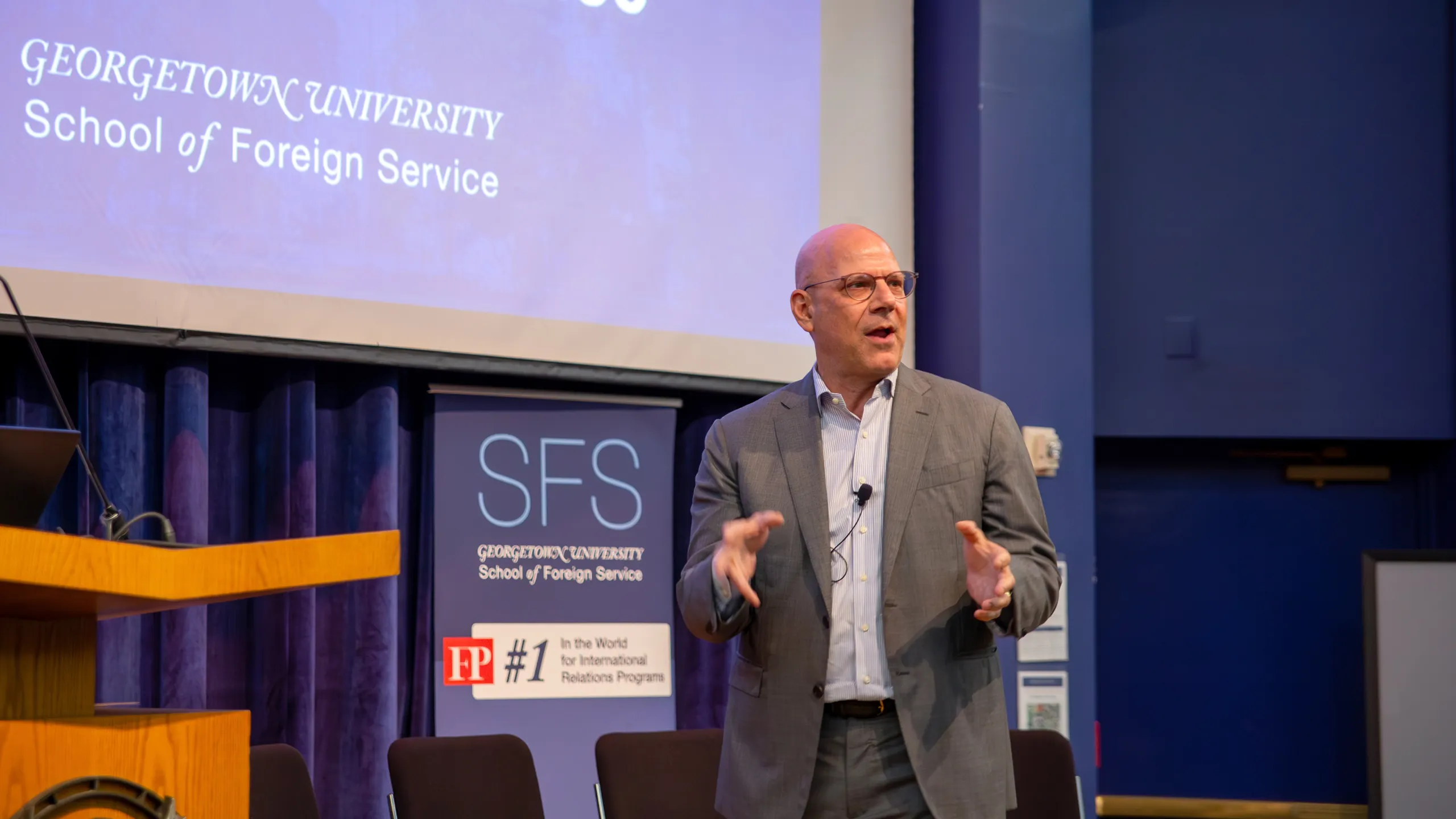 Dean Hellman speaking on stage. Behind him a banner of the School of Foreign Service