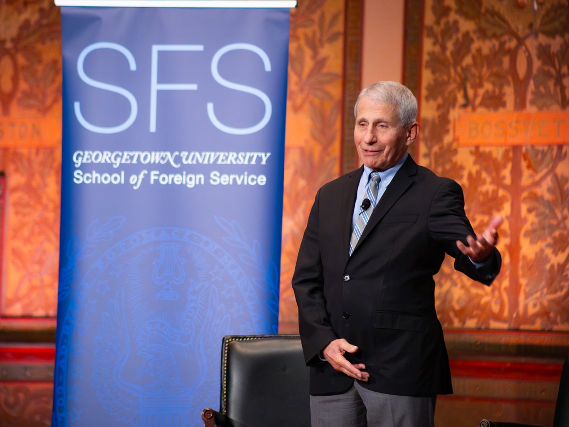 Dr. Fauci, standing on stage, behind him a banner of Georgetown University's School of Foreign Service