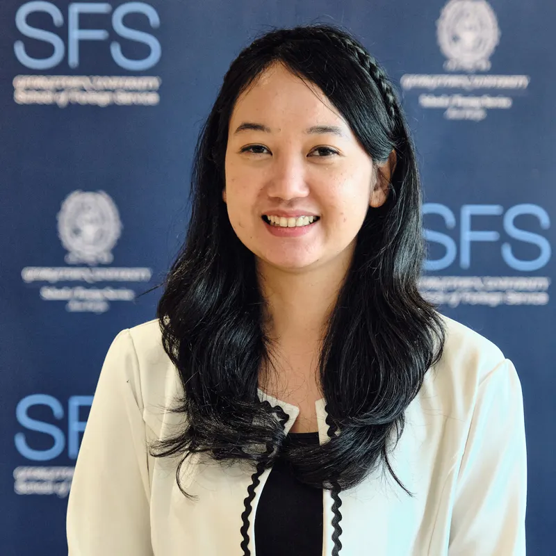 Headshot of Halida Nufaisa smiling, in front of a backdrop with the Georgetown and School of Foreign Service logo.