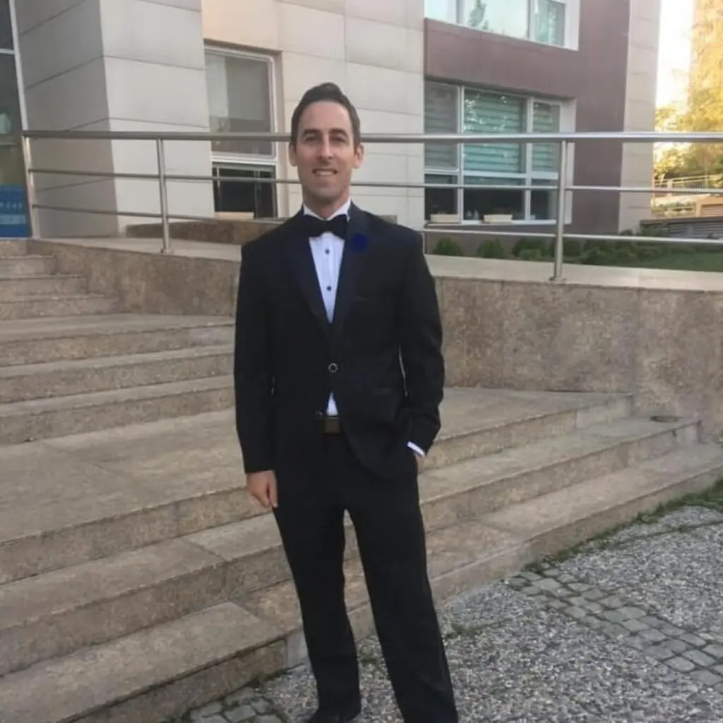 Jon Paul Bernard wearing a black suit standing in front of some steps.