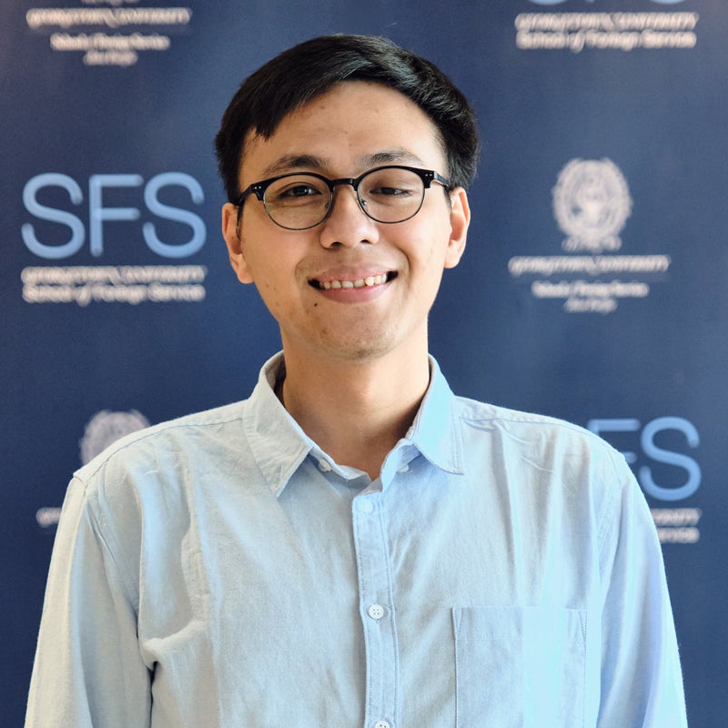 Headshot of Joshua Mangkubudi smiling, in front of a backdrop with the Georgetown and School of Foreign Service logo.