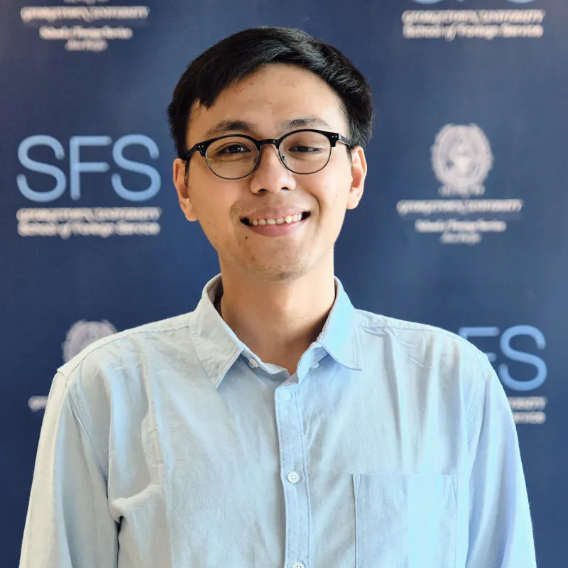 Headshot of Joshua Mangkubudi smiling, in front of a backdrop with the Georgetown and School of Foreign Service logo.
