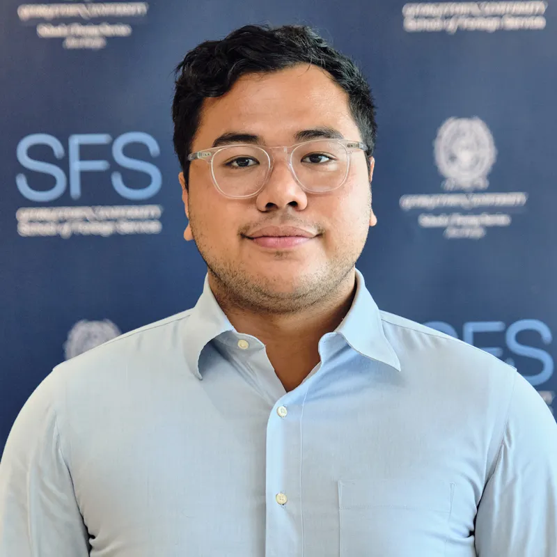 Headshot of Robbi Ramadhan, in front of a backdrop with the Georgetown and School of Foreign Service logo.