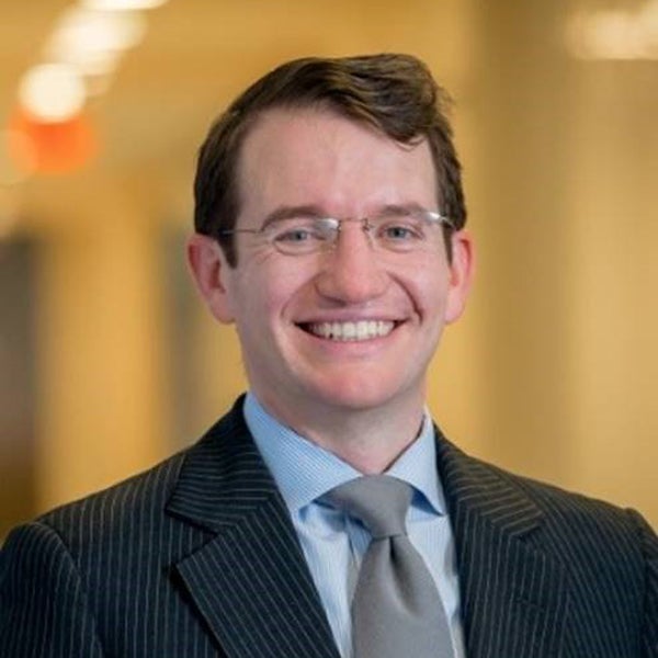 Headshot of a smiling Brendan Mullen, wearing a suit and tie.