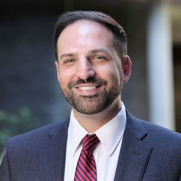 Headshot of a smiling Christopher Griffin wearing a suit.
