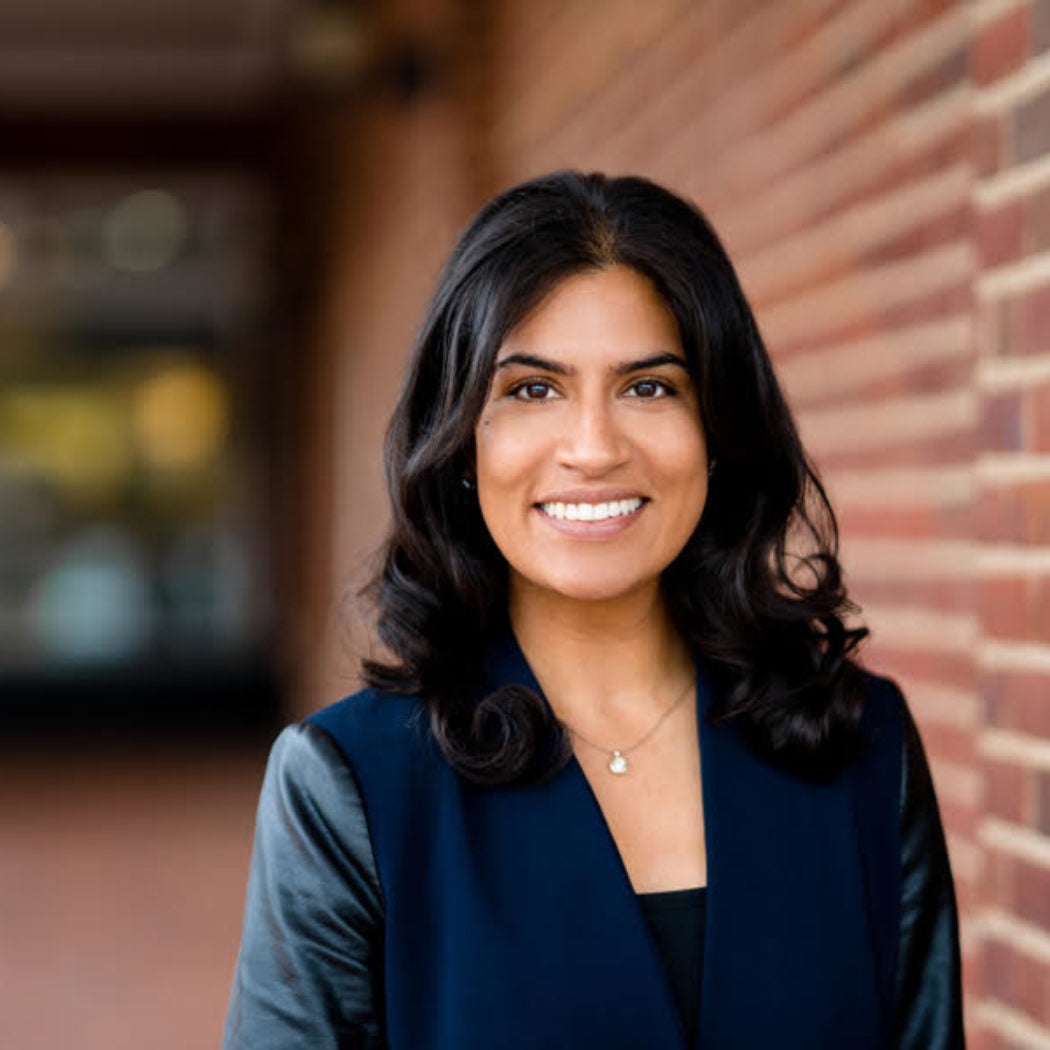 Headshot of Rehana Nathoo, smiling, wearing a black and navy blue blouse.