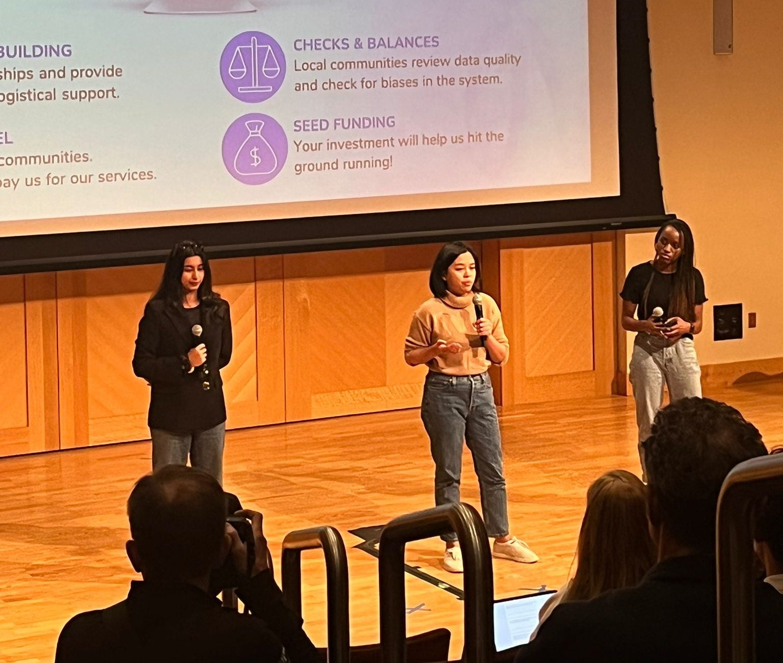 Photo of three students presenting on stage.