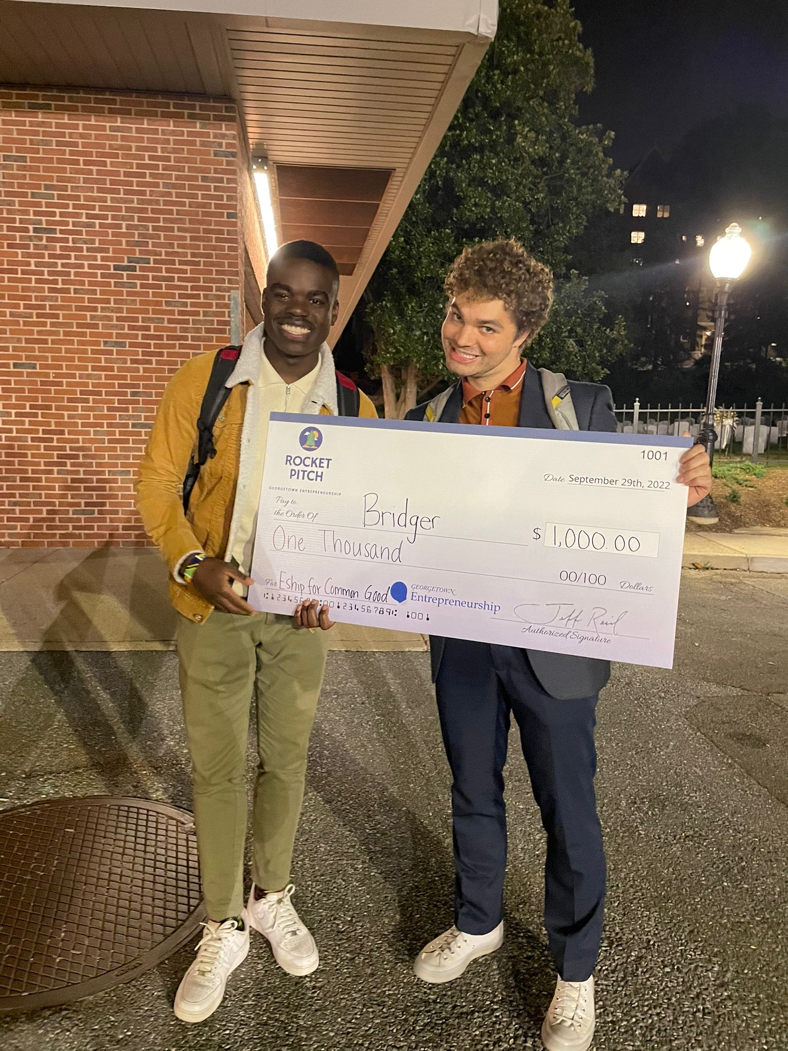Photo of two students holding their award check of 1,000 dollars for their project Bridger.