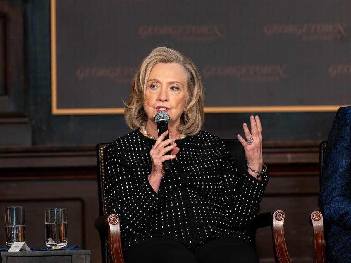 Hilary Clinton speaking at a panel, she is sitting down, behind her a wall with the Georgetown University logo