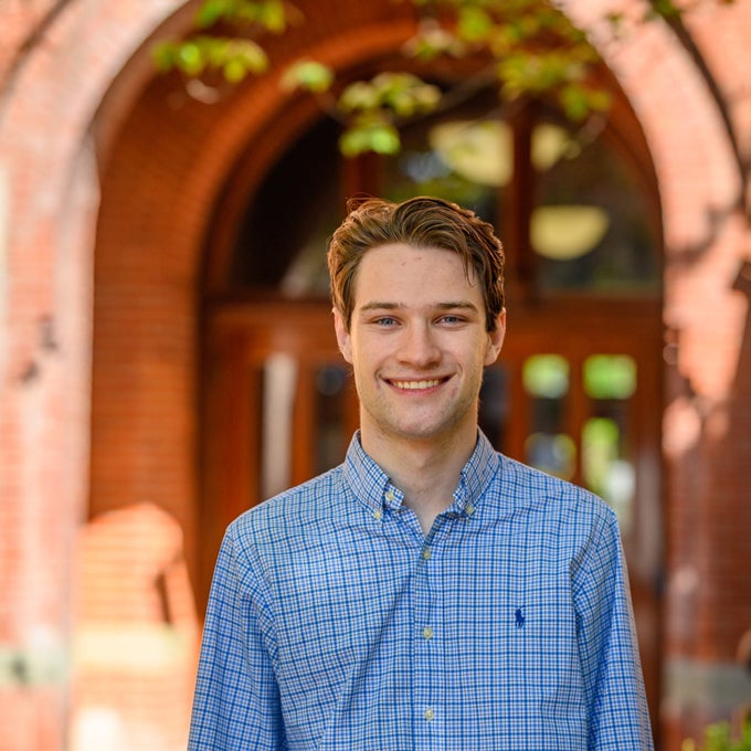 Headshot of a smiling Kenton Kaplan on a sunny day wearing a blue buttoned up shirt