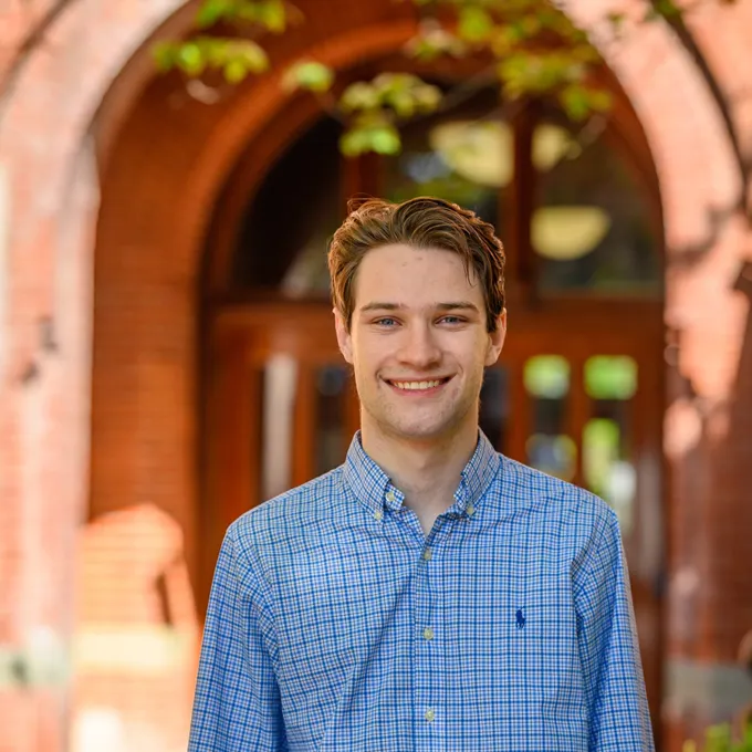 Headshot of a smiling Kenton Kaplan on a sunny day wearing a blue buttoned up shirt