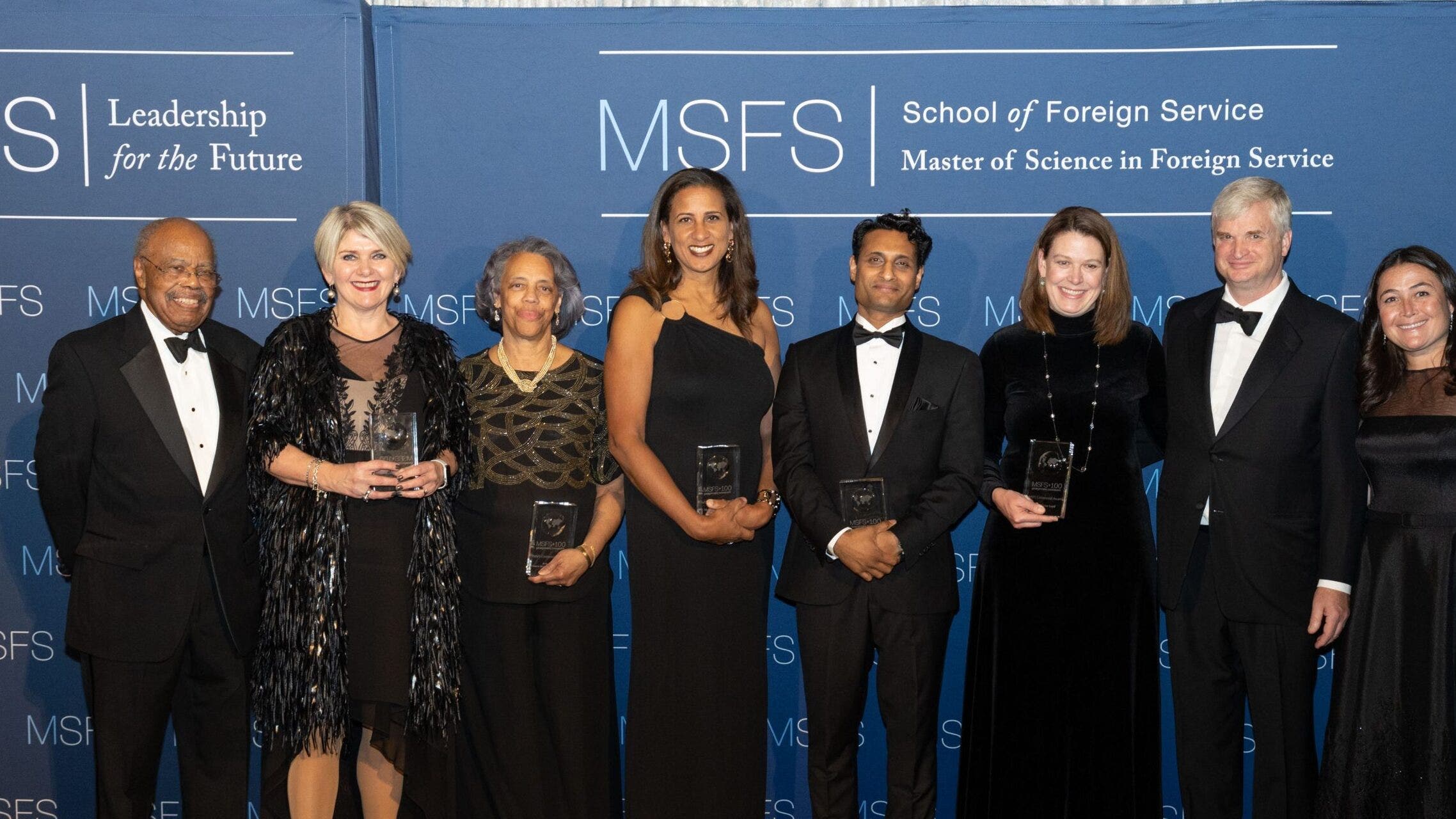 Photo of 8 people in front of a banner to celebrate MSFS Centennial Honorees.