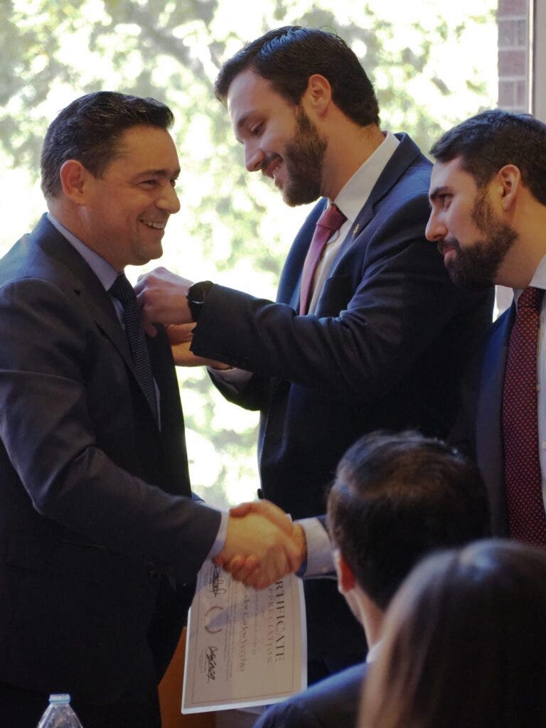 MSFS student Raphael putting a pin on Ambassador Vecchio's suit.