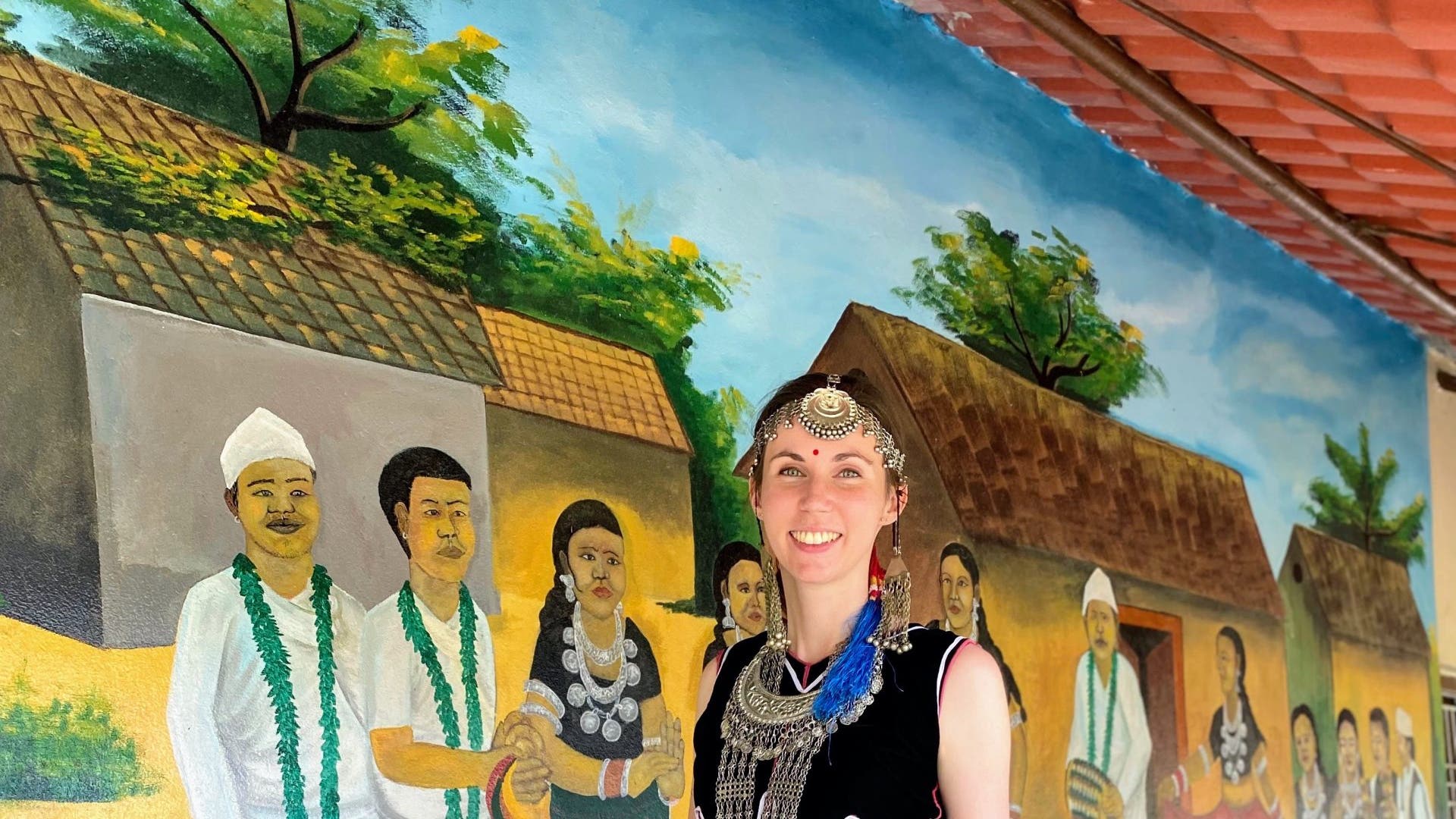 Therese in a traditional dress, posing in front of a wall.